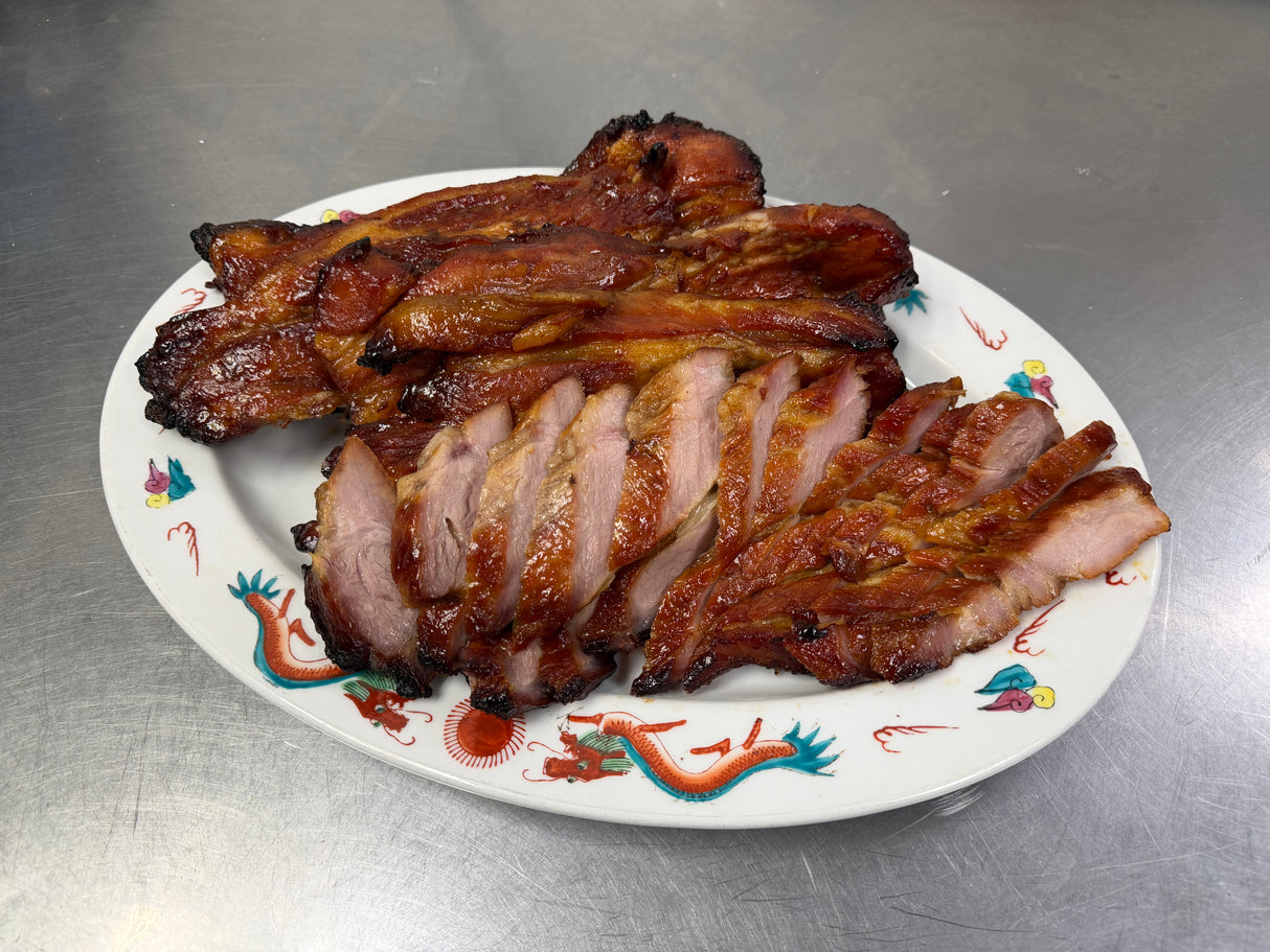 Sliced and whole Cantonese BBQ pork on a decorative plate.