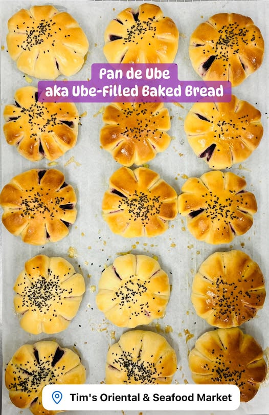 Pan de Ube (Ube-filled baked bread) with black sesame seeds on a baking tray, branded as Tim's Oriental & Seafood Market.