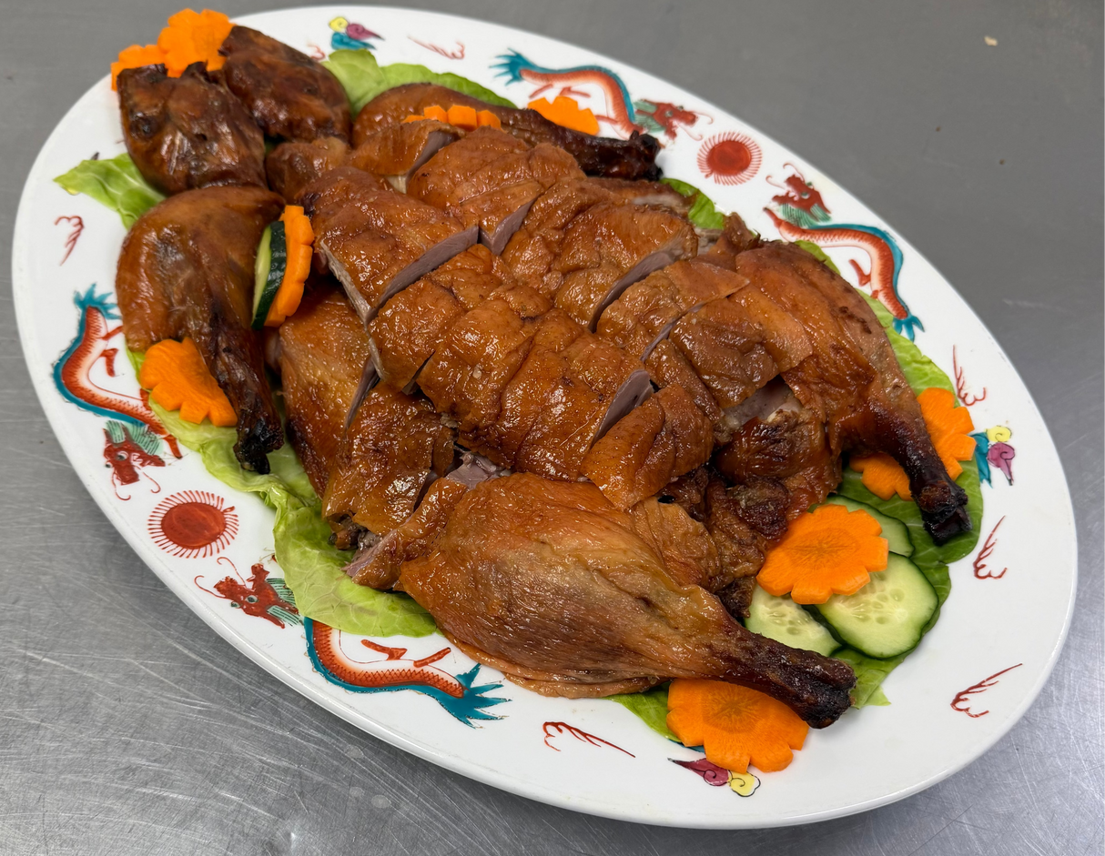 Plated dish of Cantonese roast duck with vegetable garnishes on a decorative plate.